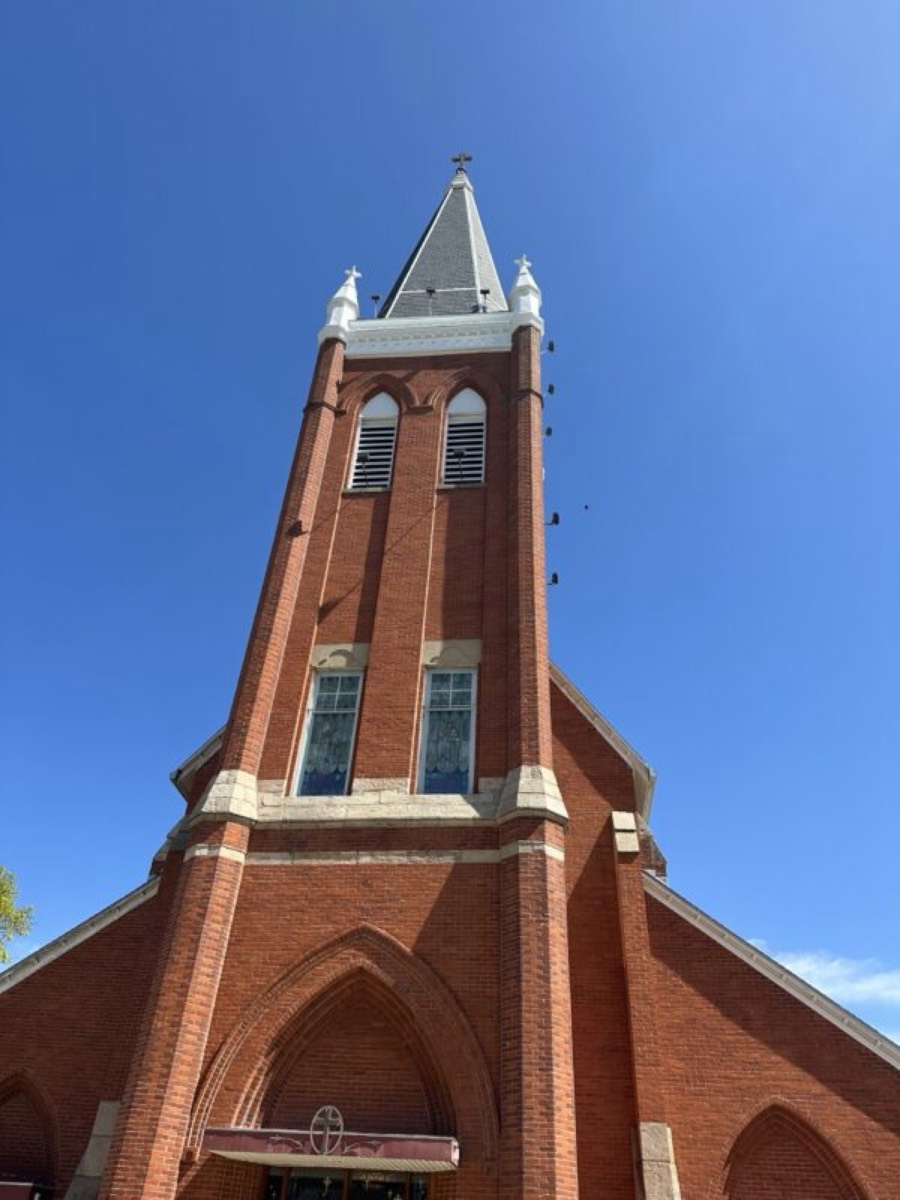Brick church with tall steeple and cross