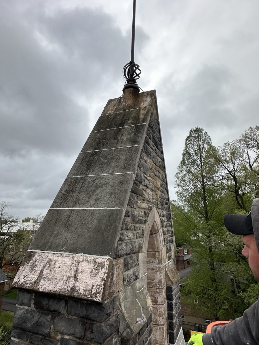 Mason repairing a stone spire cap at height